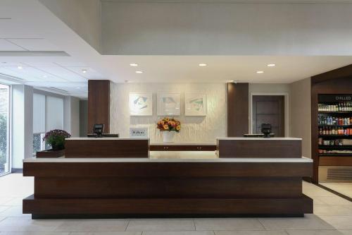a lobby with a counter with flowers on it at Hilton Garden Inn Melville in Plainview