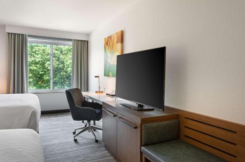 a hotel room with a desk with a flat screen tv at Hilton Garden Inn Melville in Plainview