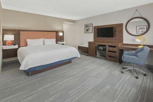 a hotel room with a bed and a tv and a chair at Hampton Inn & Suites Macon I-75 North in Macon