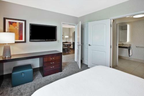a hotel room with a bed and a desk with a television at Embassy Suites Columbus - Airport in Columbus