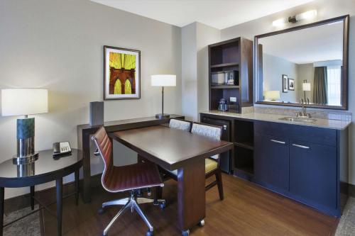 a room with a desk and a table and a mirror at Embassy Suites Columbus - Airport in Columbus