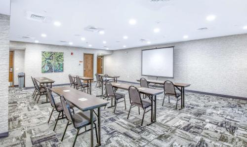 a conference room with tables and chairs and a screen at Home2 Suites by Hilton Mobile West I-10 Tillmans Corner in Tillmans Corner