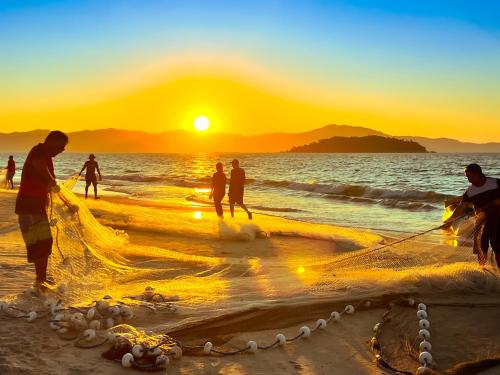 a group of people on the beach at sunset at Hotel Palace 1 in Florianópolis