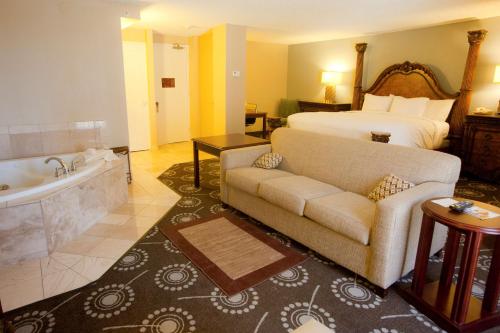 a hotel room with a bed and a couch and a tub at DoubleTree by Hilton Midland Plaza in Midland