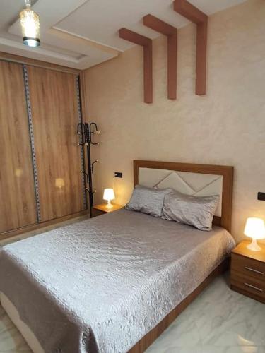 a bedroom with a bed with two tables and two lamps at Appartement Dar Meknès in Meknès
