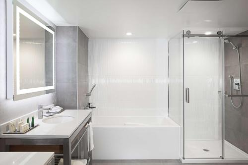 a white bathroom with a shower and a sink at Hilton Montreal/Laval in Laval