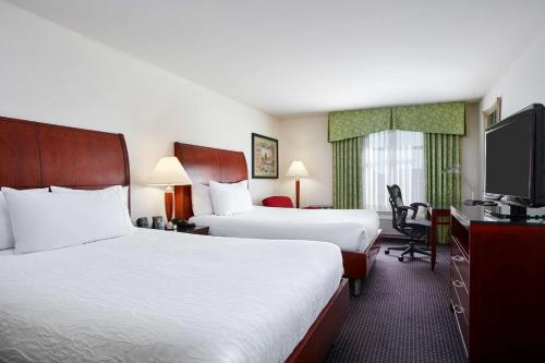 a hotel room with two beds and a flat screen tv at Hilton Garden Inn Rockville - Gaithersburg in Rockville