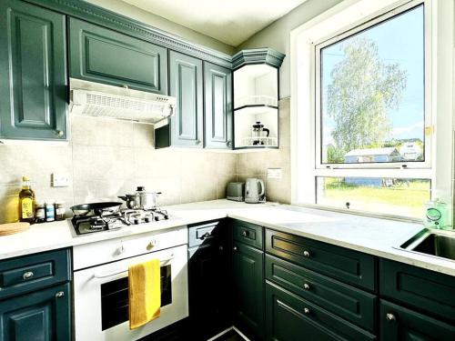 eine Küche mit grünen Schränken, einem Waschbecken und einem Fenster in der Unterkunft Cosy bright home in Murrayfield in Edinburgh