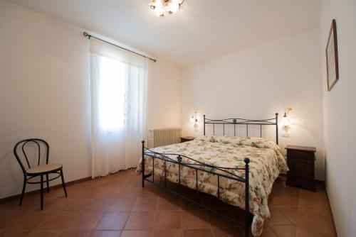 a bedroom with a bed and a chair and a window at Il Casale Degli Ulivi B&B in Ascoli Piceno