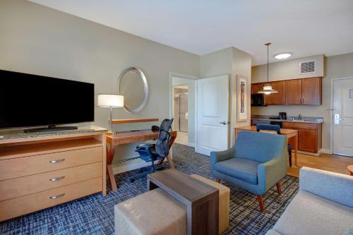 a living room with a flat screen tv and a chair at Homewood Suites Dallas-Frisco in Frisco