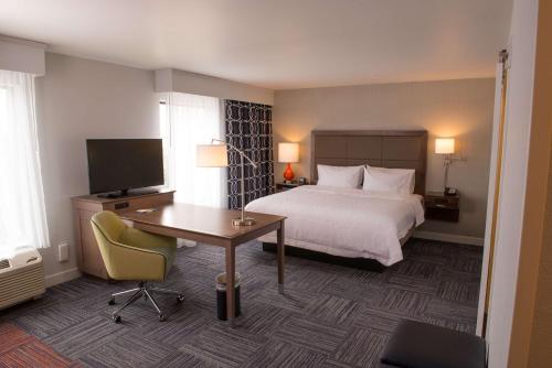 Habitación de hotel con cama, escritorio y TV. en Hampton Inn & Suites Bay City en Bay City