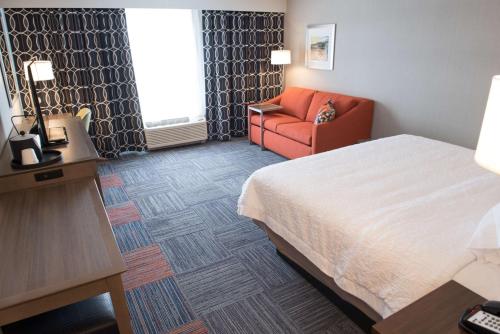 a hotel room with a bed and a chair at Hampton Inn & Suites Bay City in Bay City