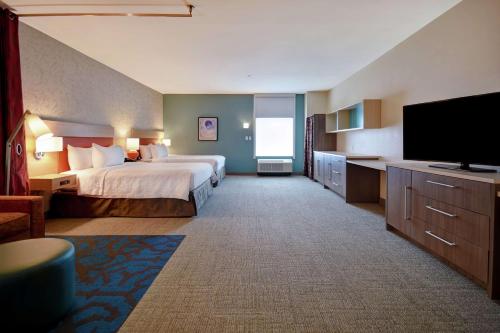 a hotel room with a bed and a flat screen tv at Home2 Suites by Hilton Harvey New Orleans Westbank in Harvey