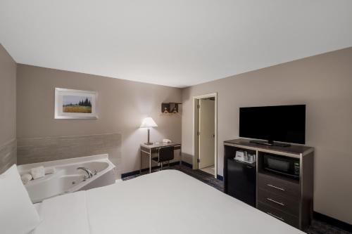 a hotel room with a bed and a flat screen tv at Americas Best Value Inn Farmington in Farmington