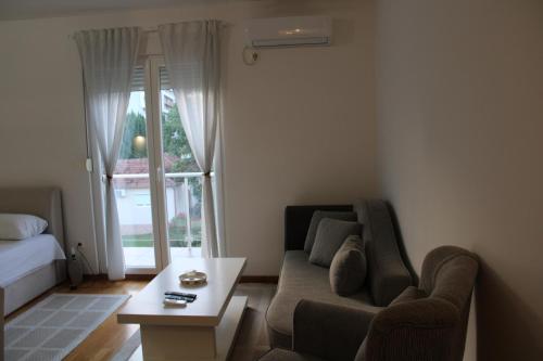 - un salon avec un canapé, une table et une fenêtre dans l'établissement Delta studio apartman, à Podgorica