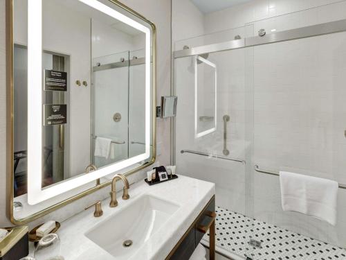 a white bathroom with a sink and a shower at Tulsa Club Hotel Curio Collection By Hilton in Tulsa