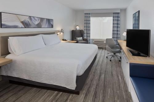 a hotel room with a bed and a desk with a television at Hilton Garden Inn Birmingham SE/Liberty Park in Birmingham