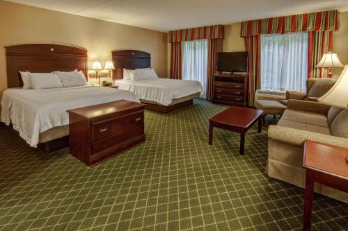 a hotel room with two beds and a couch at Hampton Inn Cambridge in Cambridge