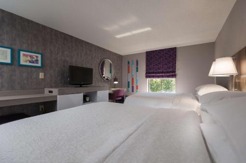 a hotel room with two beds and a television at Hampton Inn East Windsor in East Windsor