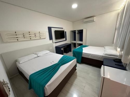 a hotel room with two beds and a television at Zurique Sorocaba Hotel in Sorocaba