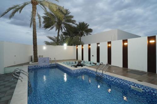 a swimming pool with blue tiles and palm trees at al dorar farm 