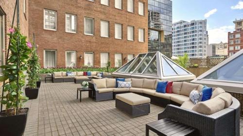 eine Terrasse mit Sofas und Tischen auf einem Gebäude in der Unterkunft Vogue Hotel Montreal Downtown, Curio Collection by Hilton in Montreal