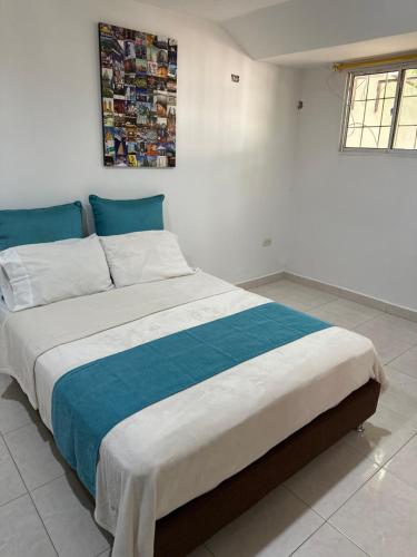 a bedroom with a large bed with blue and white sheets at Casa de LuCa apartamento familiar in Santa Marta