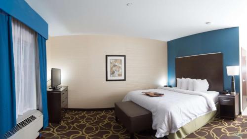a hotel room with a large bed and blue walls at Hampton Inn & Suites East Gate Regina in Regina