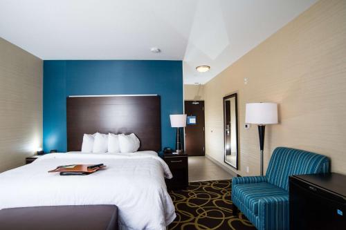 a hotel room with a bed and a chair at Hampton Inn & Suites East Gate Regina in Regina
