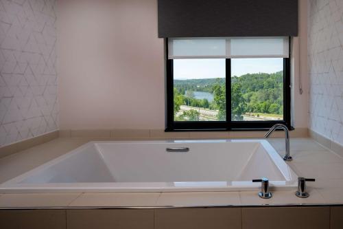 Hilton Asheville Biltmore Park في أشفيل: حوض استحمام كبير في حمام مع نافذة