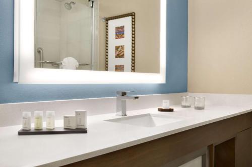 a bathroom with a white sink and a mirror at Embassy Suites San Antonio Airport in San Antonio