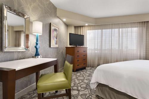 a hotel room with a bed and a desk and a television at Embassy Suites San Antonio Airport in San Antonio