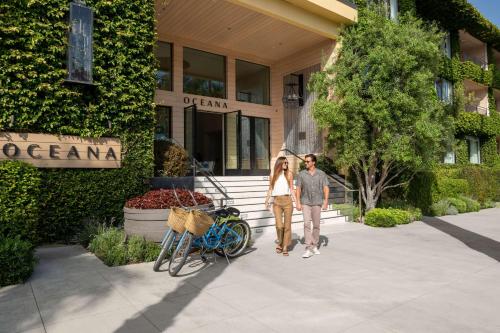 Oceana Santa Monica, LXR Hotels & Resorts في لوس أنجلوس: رجل وامرأة يسيران أمام مبنى