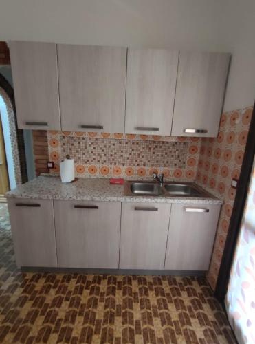 a kitchen with white cabinets and a sink at Sagittario House in Torre delle Stelle