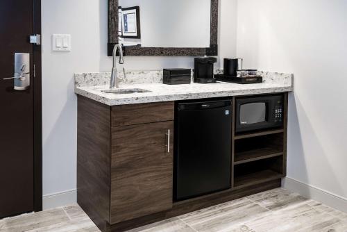 a bathroom with a sink and a microwave at Embassy Suites By Hilton College Station in College Station