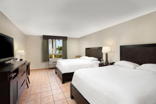 a hotel room with two beds and a flat screen tv at Rincon Beach Resort in Rincon