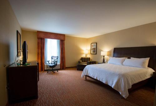 a hotel room with a bed and a television at Hilton Garden Inn Watertown in Watertown