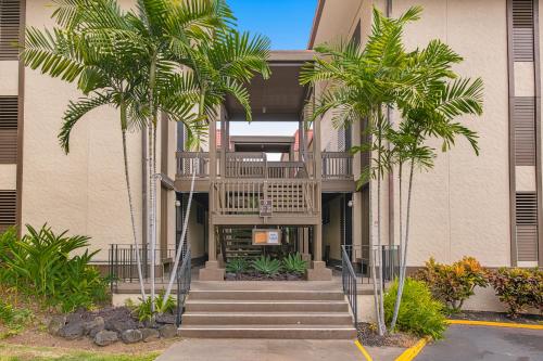 a building with stairs and palm trees in front of it at Kona Mansions D-226 in Kailua-Kona