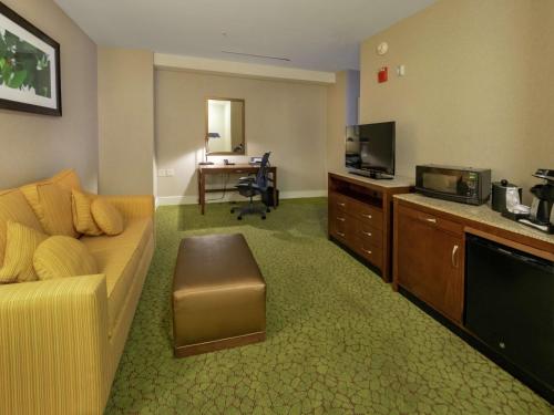 a living room with a couch and a tv and a desk at The Hilton Garden Inn Buffalo-Downtown in Buffalo