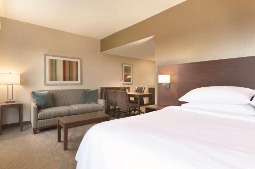 ノース・カントンにあるEmbassy Suites by Hilton Akron Canton Airportのベッドとリビングルームが備わるホテルルームです。