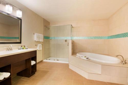 a bathroom with a tub and a sink at Embassy Suites Corpus Christi in Corpus Christi