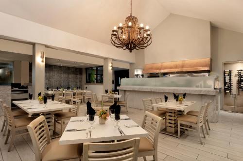 a restaurant with white tables and chairs and a chandelier at Rincon Beach Resort in Rincon