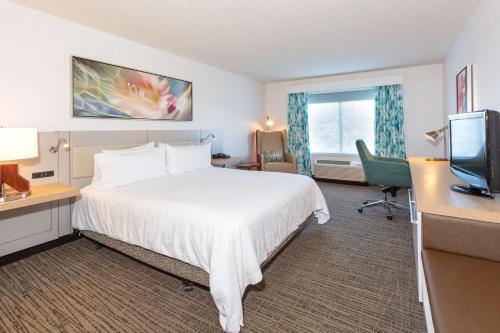 a hotel room with a bed and a desk and a television at Hilton Garden Inn Daytona Beach Airport in Daytona Beach