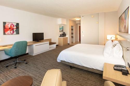 a hotel room with a bed and a desk and a television at Hilton Garden Inn Daytona Beach Airport in Daytona Beach