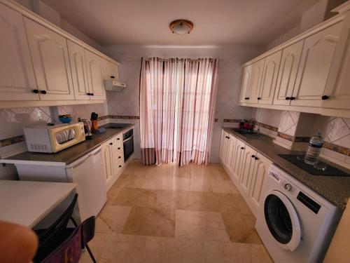 cocina con armarios blancos, lavadora y secadora en Apartamento en Callao Salvaje, en Callao Salvaje