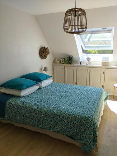 une chambre avec un lit avec des oreillers bleus et une fenêtre dans l'établissement Le Clos des Mouettes, à Calais