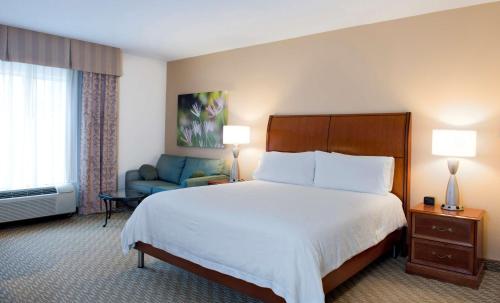 a hotel room with a bed and a blue chair at Hilton Garden Inn Rock Hill in Rock Hill