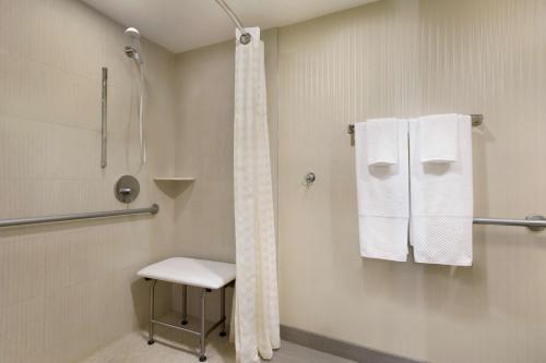 a bathroom with a shower and a chair and towels at Embassy Suites by Hilton Piscataway Somerset in Piscataway