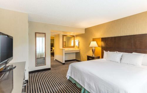 a hotel room with a bed and a flat screen tv at Embassy Suites by Hilton Piscataway Somerset in Piscataway