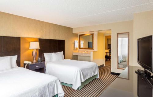 a hotel room with two beds and a flat screen tv at Embassy Suites by Hilton Piscataway Somerset in Piscataway